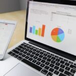 Analyzing business data on a laptop and planning on a tablet.