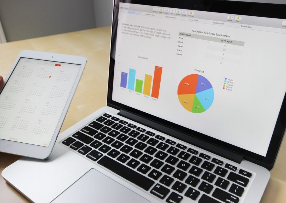 Analyzing business data on a laptop and planning on a tablet.